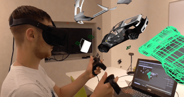 A user holds tracked controllers beside a car body, chassis and wheel model.